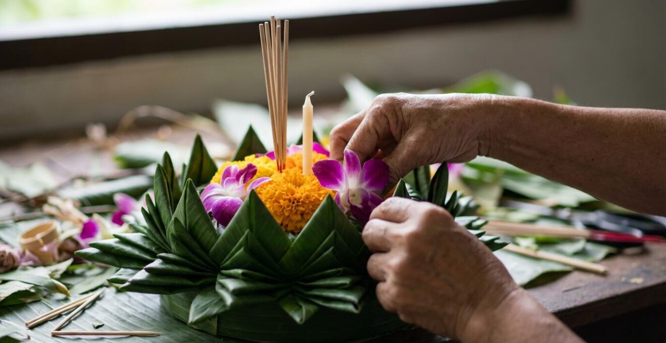 Gros plan sur un krathong traditionnel biodégradable fait de feuilles de bananier tressées avec des fleurs naturelles