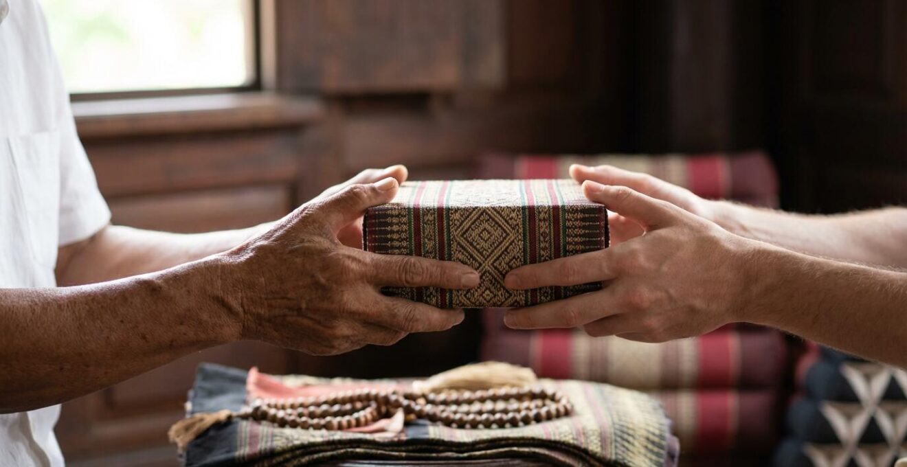 Voyageur occidental recevant un objet avec les deux mains d'une personne âgée thaïlandaise, montrant le respect traditionnel